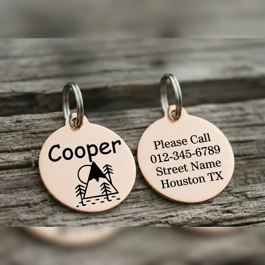 Two rose gold dog tags with engraved text on a wooden surface
