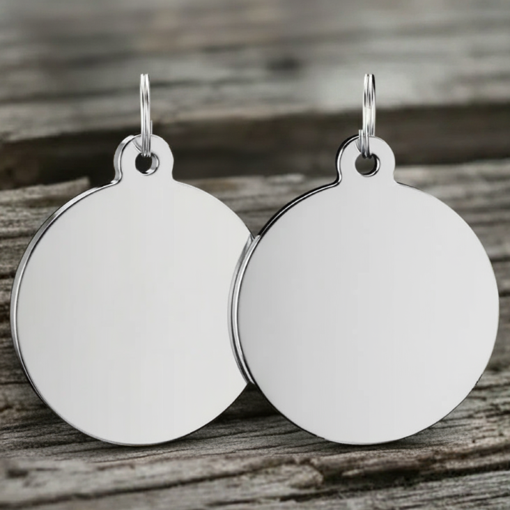 Pair of silver round dog tags on a wooden surface
