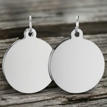 Pair of silver round dog tags on a wooden surface